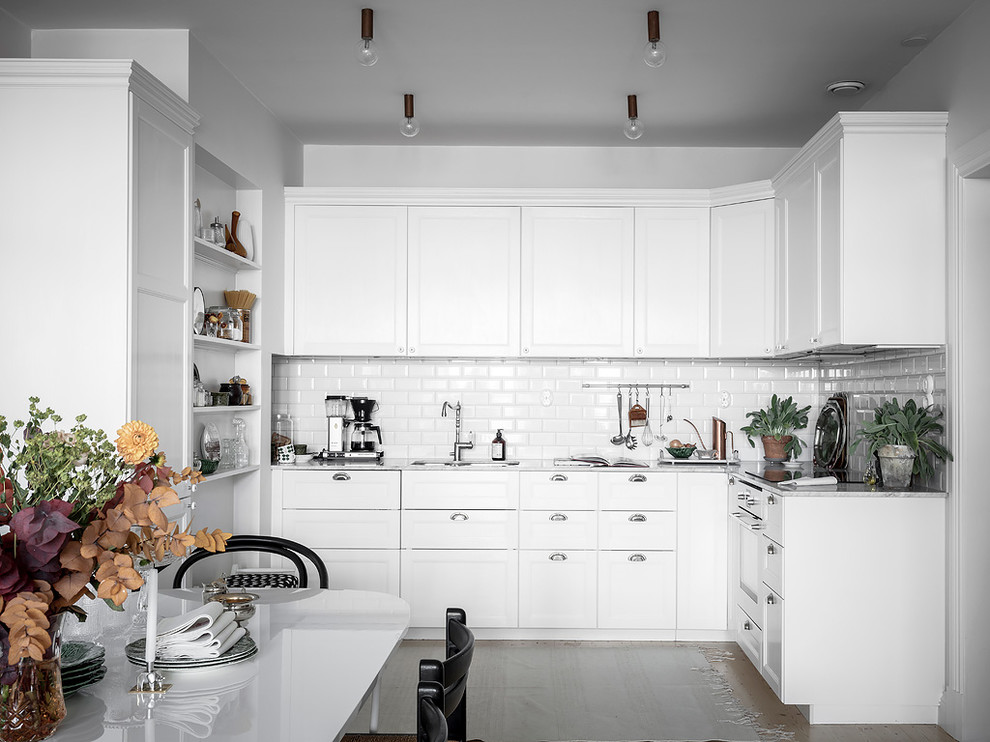 Inspiration för ett skandinaviskt vit vitt kök, med en undermonterad diskho, luckor med infälld panel, vita skåp, vitt stänkskydd, stänkskydd i tunnelbanekakel och integrerade vitvaror