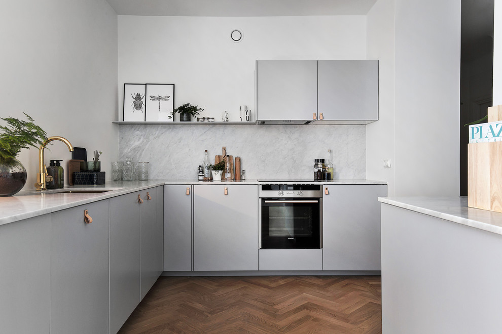 Inspiration för avskilda, stora skandinaviska l-kök, med en nedsänkt diskho, släta luckor, grå skåp, marmorbänkskiva, rostfria vitvaror och mellanmörkt trägolv