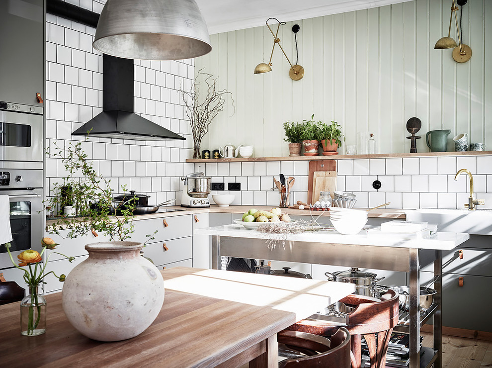 Inspiration för nordiska l-kök, med släta luckor, grå skåp, vitt stänkskydd, rostfria vitvaror och en köksö
