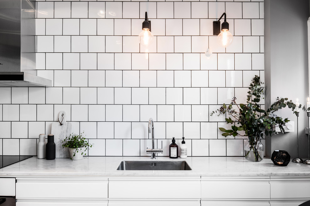 Idéer för att renovera ett litet minimalistiskt linjärt kök med öppen planlösning, med vita skåp, marmorbänkskiva, vitt stänkskydd, stänkskydd i keramik, vita vitvaror, målat trägolv och vitt golv