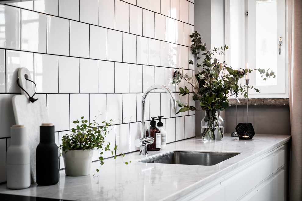 Idéer för ett litet minimalistiskt linjärt kök med öppen planlösning, med vita skåp, marmorbänkskiva, vitt stänkskydd, stänkskydd i keramik, vita vitvaror, målat trägolv och vitt golv