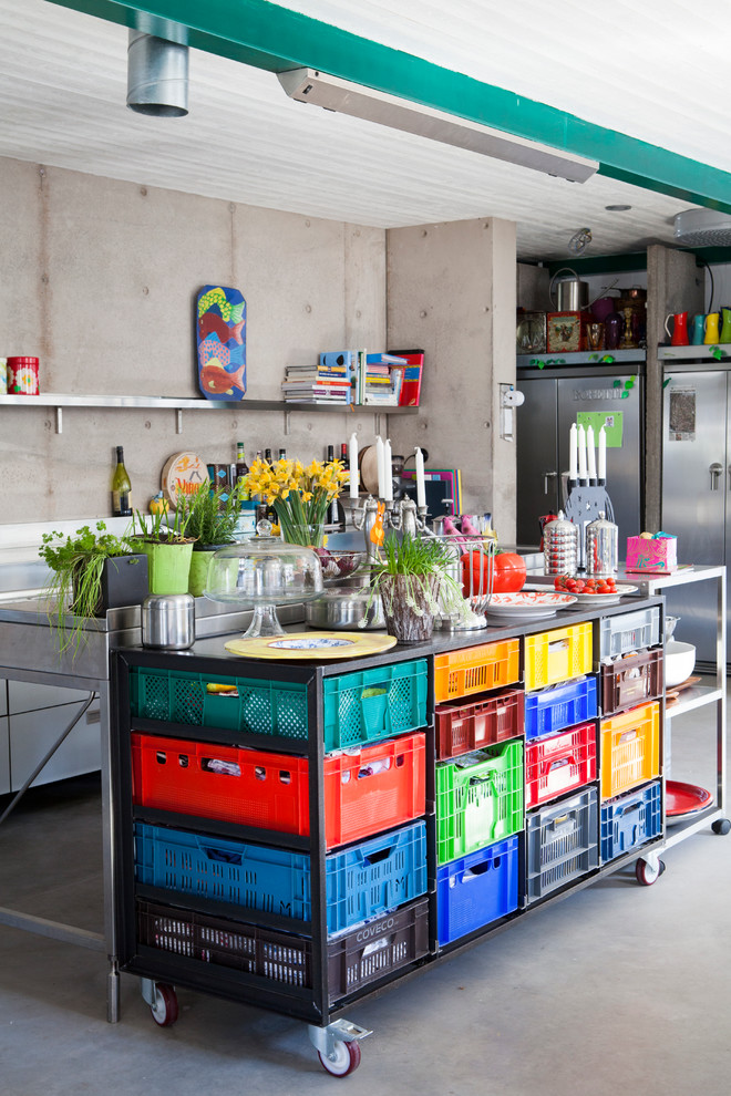 ヨーテボリにある高級な広いエクレクティックスタイルのおしゃれなキッチン (オープンシェルフ、ステンレスカウンター、シルバーの調理設備、コンクリートの床) の写真