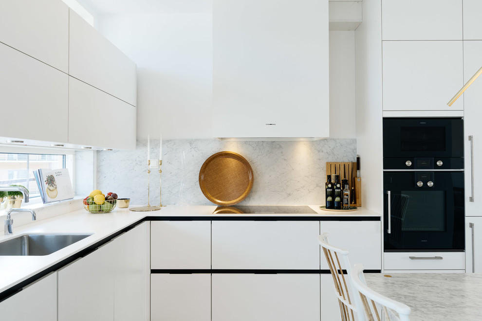 Eat-in kitchen - mid-sized contemporary eat-in kitchen idea in Stockholm with an undermount sink, flat-panel cabinets, white cabinets, white backsplash, stone slab backsplash, black appliances and no island