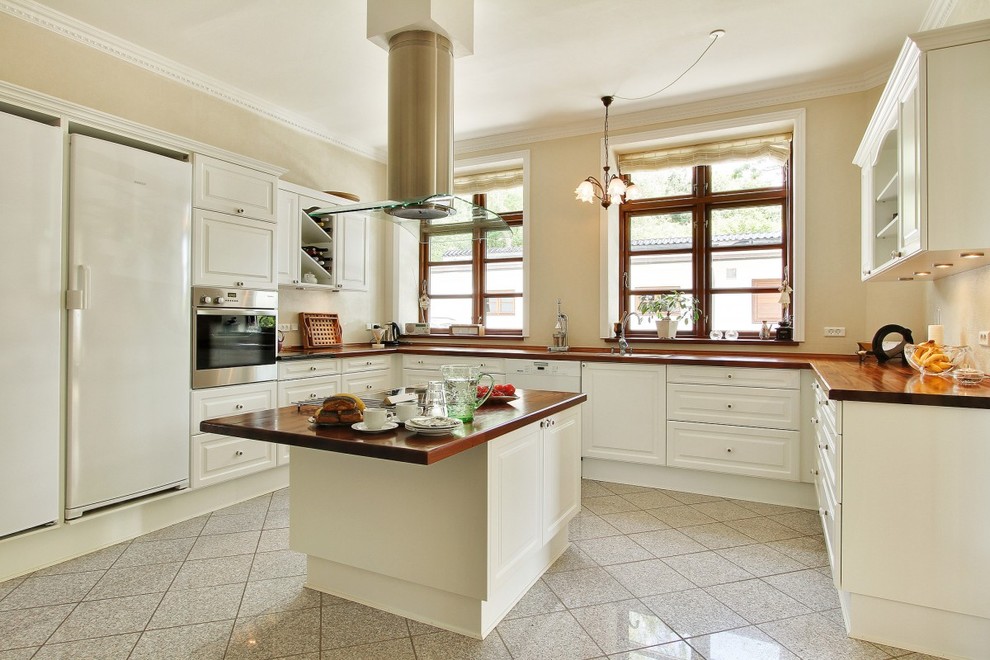 エスビャールにある高級な広いトラディショナルスタイルのおしゃれなキッチン (レイズドパネル扉のキャビネット、白いキャビネット、木材カウンター、シルバーの調理設備、ドロップインシンク、磁器タイルの床) の写真