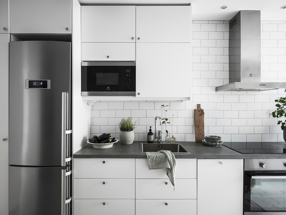 Inspiration för minimalistiska grått kök, med släta luckor, vita skåp, bänkskiva i betong, vitt stänkskydd, en nedsänkt diskho och rostfria vitvaror