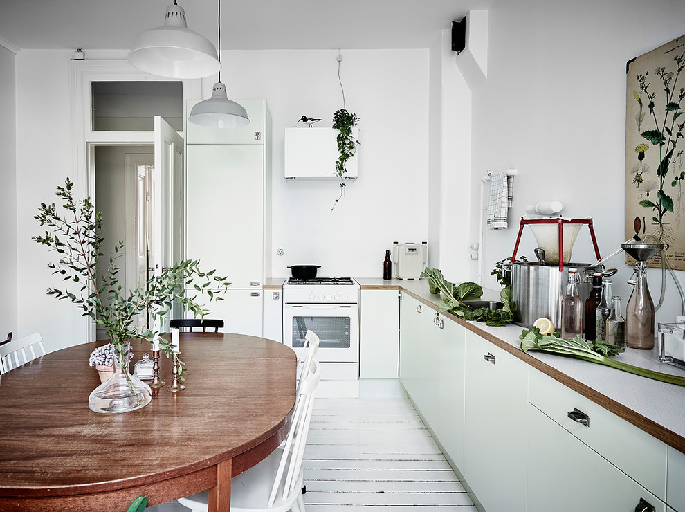 Источник вдохновения для домашнего уюта: кухня в скандинавском стиле с обеденным столом, плоскими фасадами, зелеными фасадами, деревянной столешницей, белым фартуком, деревянным полом и белым полом без острова