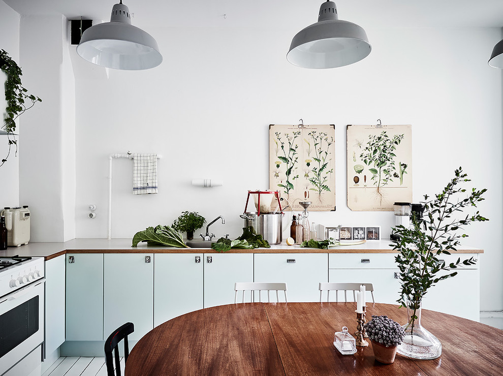 Design ideas for a medium sized scandi l-shaped kitchen/diner in Gothenburg with flat-panel cabinets, turquoise cabinets, wood worktops and no island.