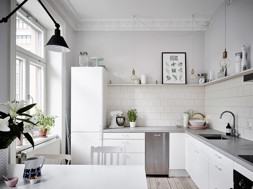 Inspiration for a medium sized scandinavian l-shaped kitchen/diner in Gothenburg with white cabinets, concrete worktops, white splashback, no island, beige floors, grey worktops, a submerged sink, flat-panel cabinets and light hardwood flooring.
