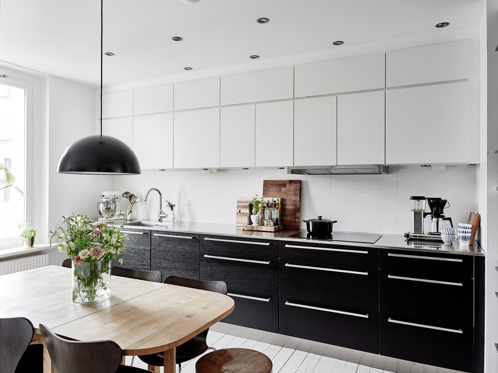 Foto på ett mellanstort minimalistiskt linjärt kök och matrum, med en undermonterad diskho, släta luckor, svarta skåp, vitt stänkskydd, rostfria vitvaror och ljust trägolv