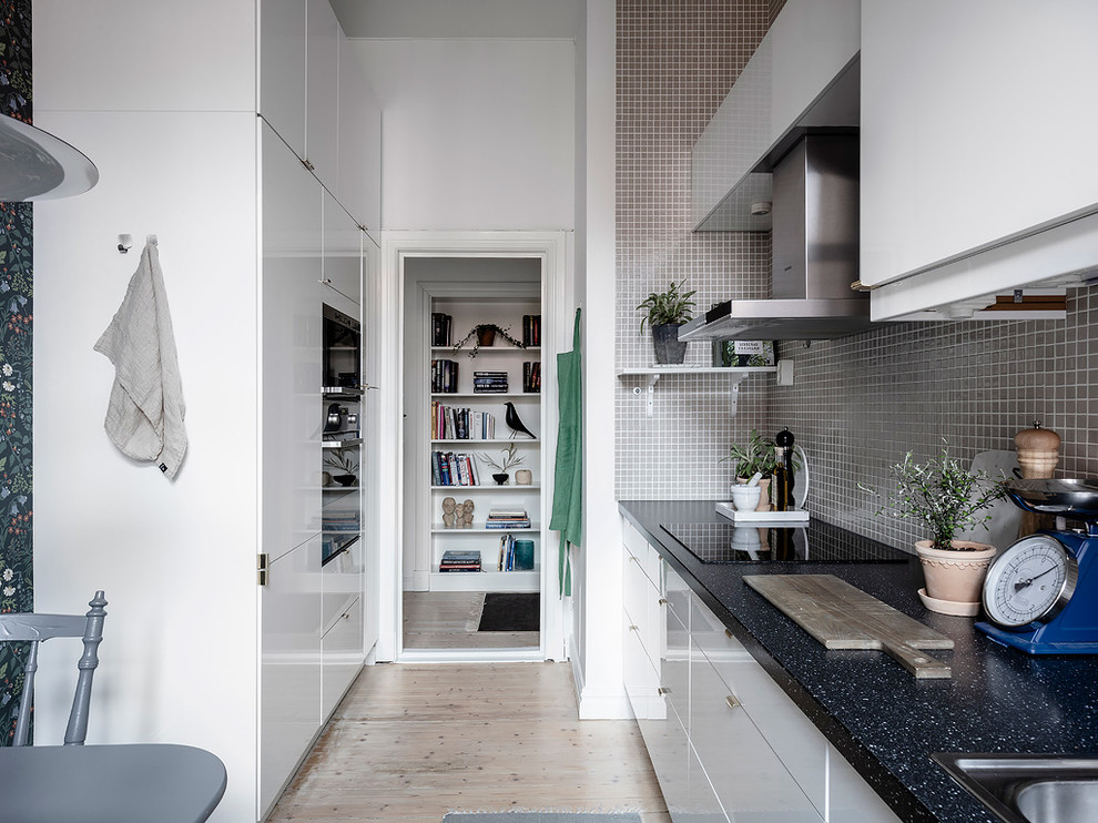 Skandinavische Küche mit Küchenrückwand in Grau, Rückwand aus Mosaikfliesen und schwarzer Arbeitsplatte in Göteborg
