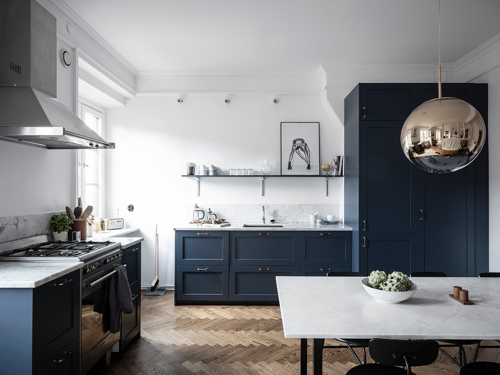 Exempel på ett stort skandinaviskt grå grått kök och matrum, med en enkel diskho, blå skåp, marmorbänkskiva, grått stänkskydd, stänkskydd i marmor, integrerade vitvaror, mellanmörkt trägolv, skåp i shakerstil och brunt golv