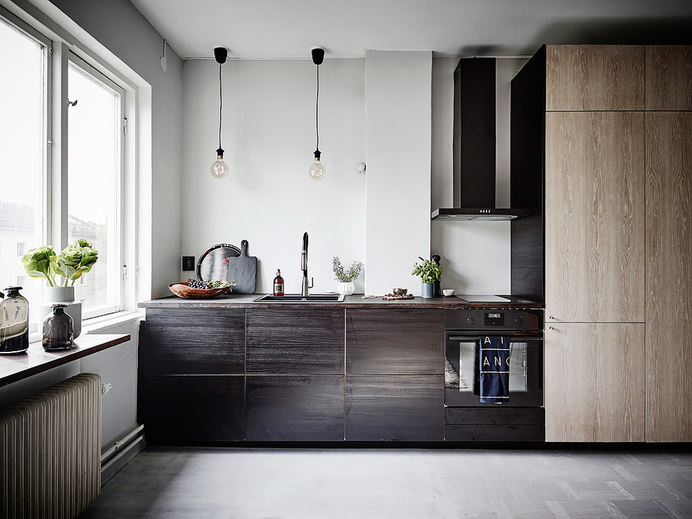 Bild på ett litet minimalistiskt linjärt kök med öppen planlösning, med en enkel diskho, släta luckor, skåp i slitet trä, träbänkskiva, stänkskydd i kalk, integrerade vitvaror, vinylgolv och grått golv
