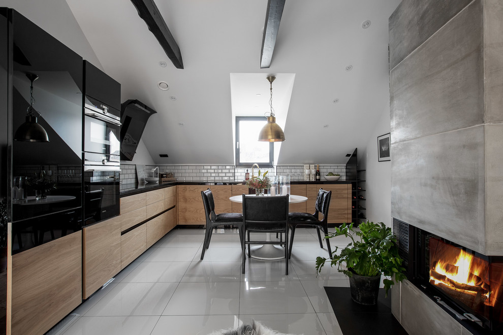 Minimalistisk inredning av ett mellanstort kök, med släta luckor, grå skåp, vitt stänkskydd, stänkskydd i tunnelbanekakel och svarta vitvaror