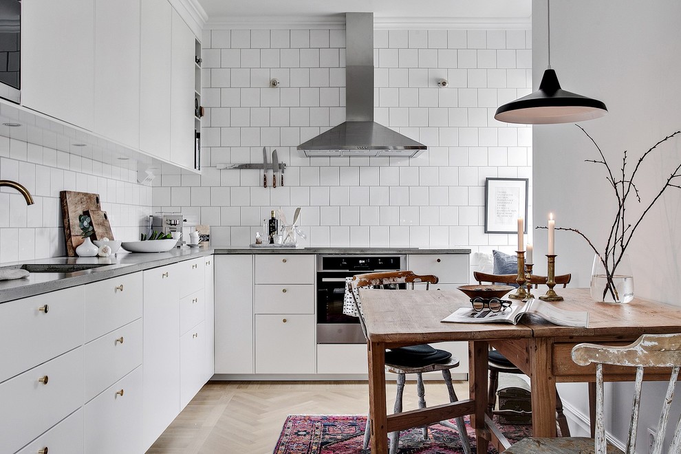 Immagine di una cucina nordica con ante lisce, ante bianche, parquet chiaro, nessuna isola, pavimento beige e paraspruzzi bianco