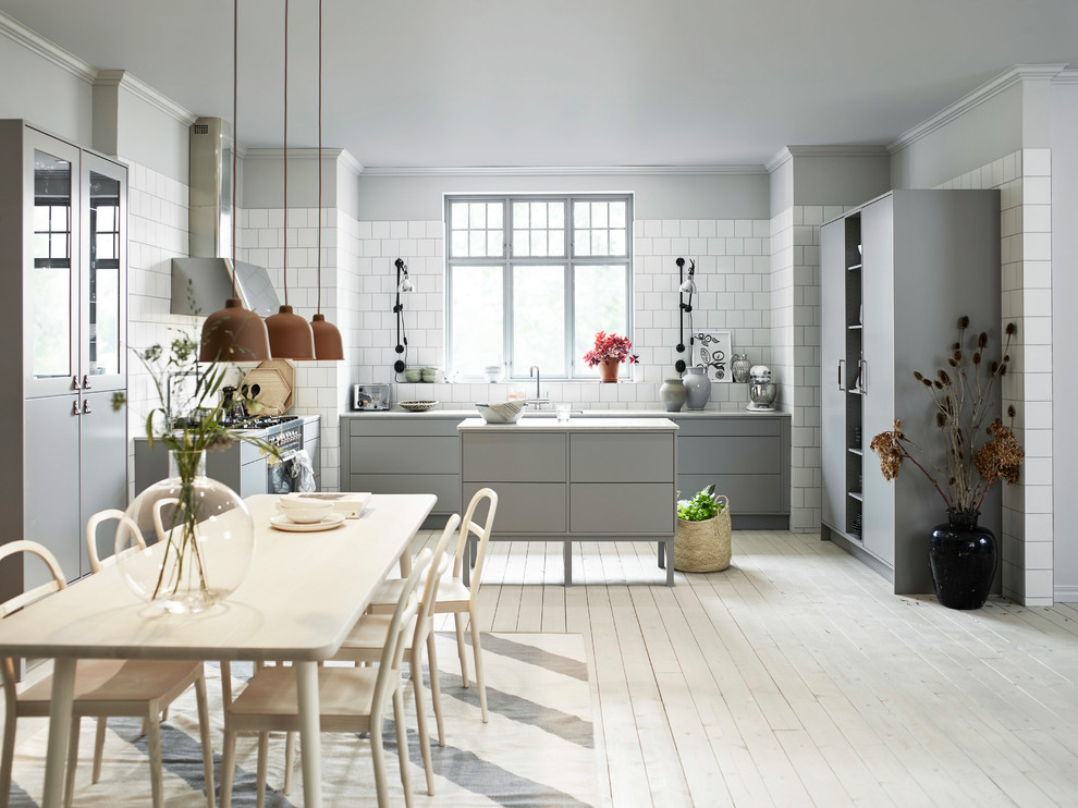Foto på ett stort minimalistiskt kök och matrum, med släta luckor, grå skåp, vitt stänkskydd och en köksö
