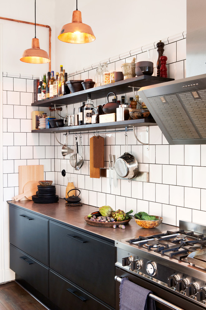 Einzeilige, Kleine Industrial Küche ohne Insel mit flächenbündigen Schrankfronten, schwarzen Schränken, Küchenrückwand in Weiß, Küchengeräten aus Edelstahl und braunem Holzboden in Stockholm
