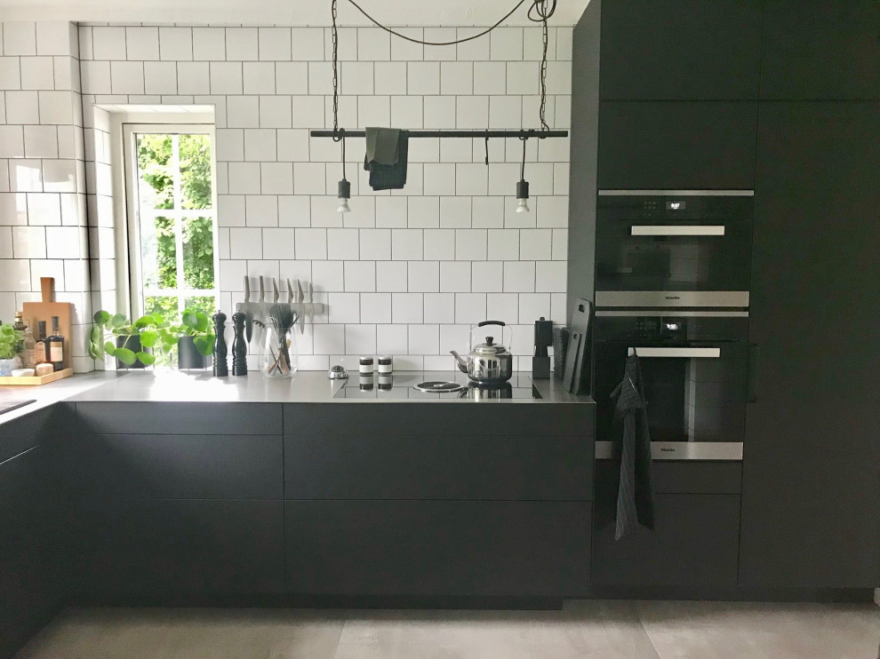 Scandi kitchen/diner in Malmo with a submerged sink, flat-panel cabinets, black cabinets, stainless steel worktops, stainless steel appliances, ceramic flooring, no island and black worktops.