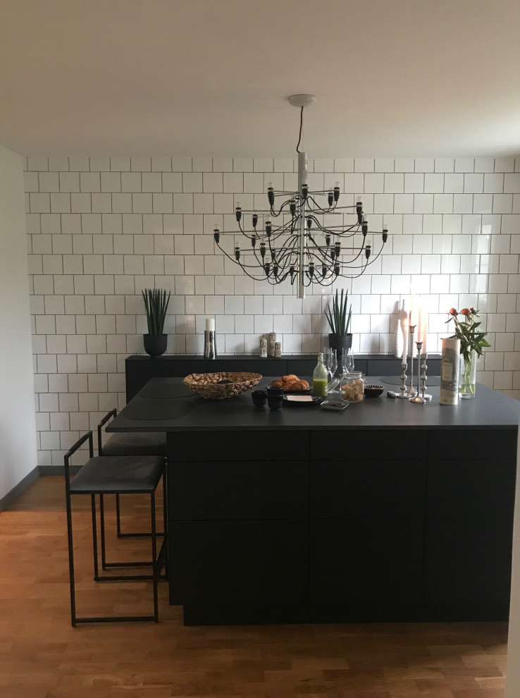 Bild på ett skandinaviskt svart svart kök och matrum, med en undermonterad diskho, släta luckor, svarta skåp, bänkskiva i rostfritt stål, rostfria vitvaror och klinkergolv i keramik