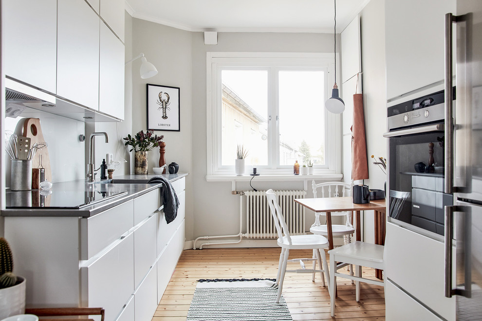 Foto på ett mellanstort skandinaviskt kök och matrum, med släta luckor, vita skåp, ljust trägolv, beiget golv och en enkel diskho