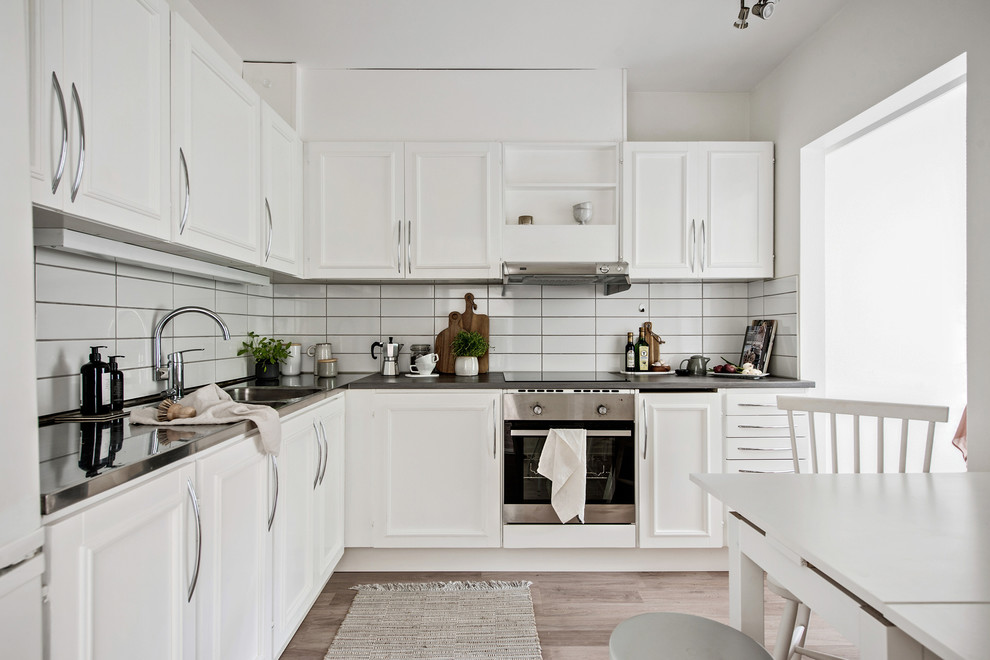 Idéer för ett mellanstort minimalistiskt kök, med luckor med profilerade fronter, vita skåp, bänkskiva i rostfritt stål och vitt stänkskydd