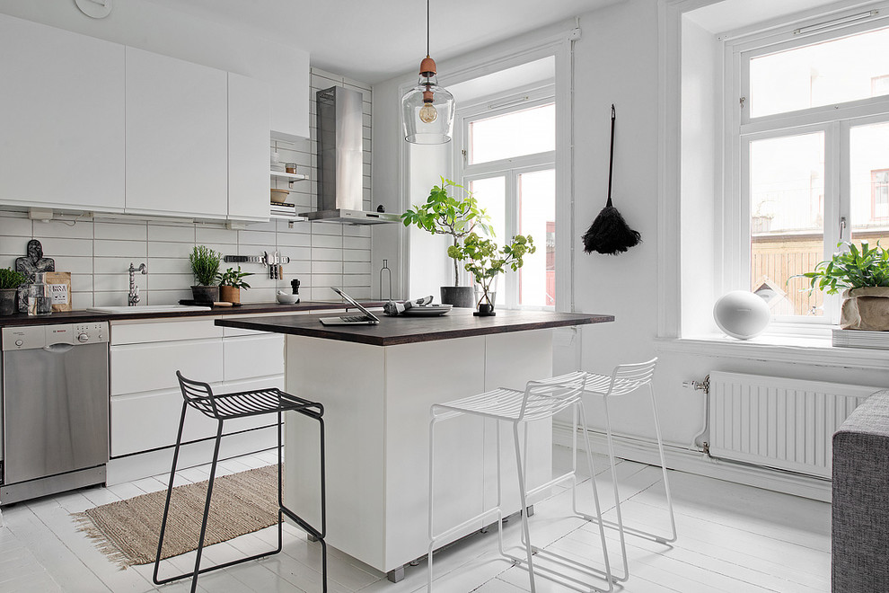 Foto på ett mellanstort skandinaviskt linjärt kök och matrum, med släta luckor, vita skåp, träbänkskiva, rostfria vitvaror, målat trägolv och en köksö