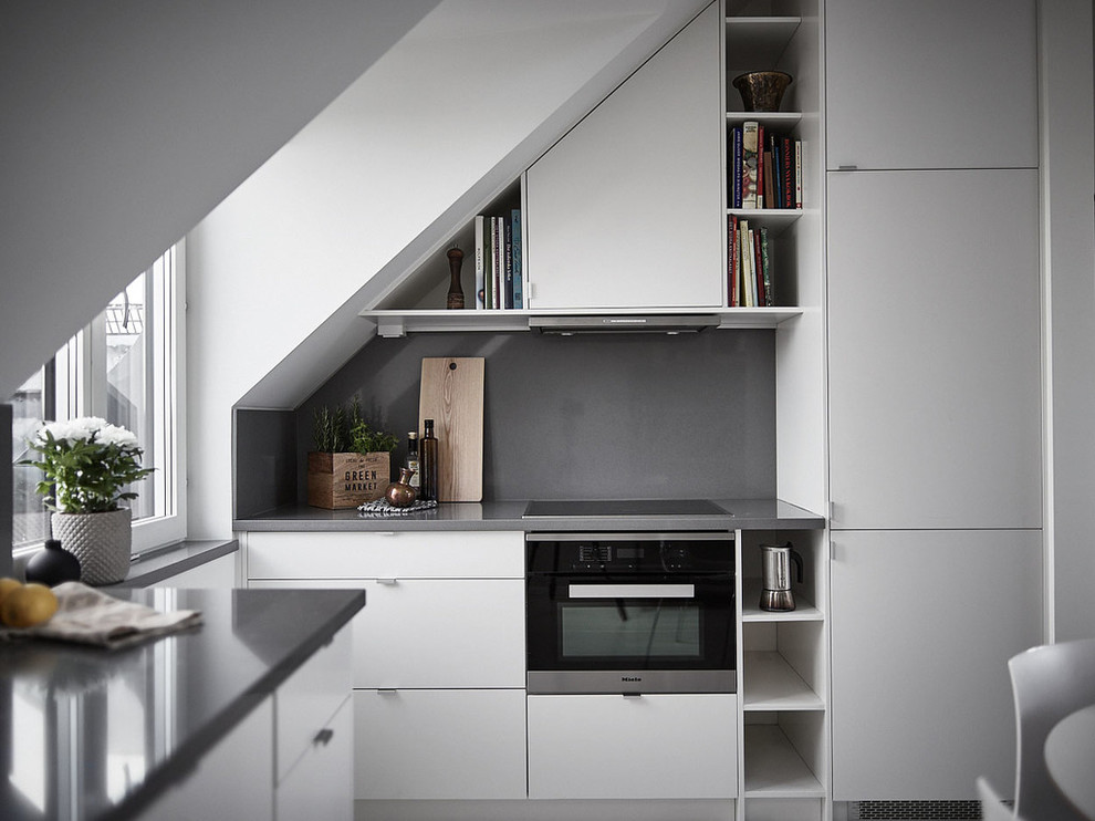ストックホルムにある小さな北欧スタイルのおしゃれなキッチン (フラットパネル扉のキャビネット、白いキャビネット、グレーのキッチンパネル、ガラス板のキッチンパネル、シルバーの調理設備、アイランドなし、グレーのキッチンカウンター) の写真