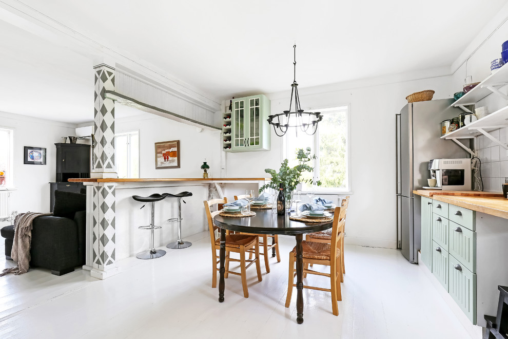 Minimalistisk inredning av ett mellanstort linjärt kök med öppen planlösning, med gröna skåp, träbänkskiva, vitt stänkskydd, rostfria vitvaror, en halv köksö, vitt golv och målat trägolv