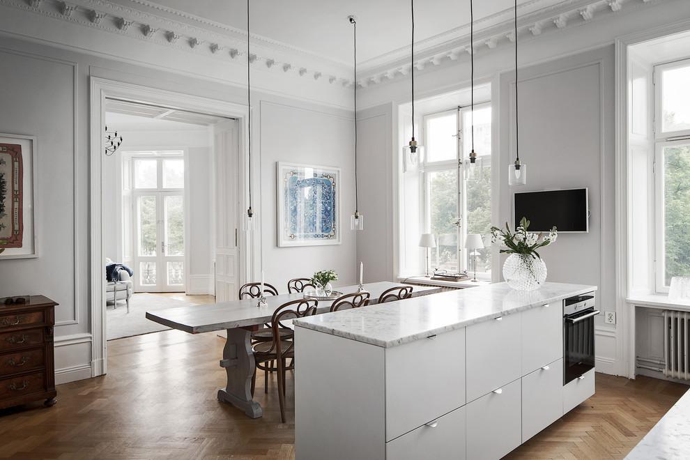 Inredning av ett klassiskt stort linjärt kök och matrum, med marmorbänkskiva, rostfria vitvaror, mellanmörkt trägolv och en köksö