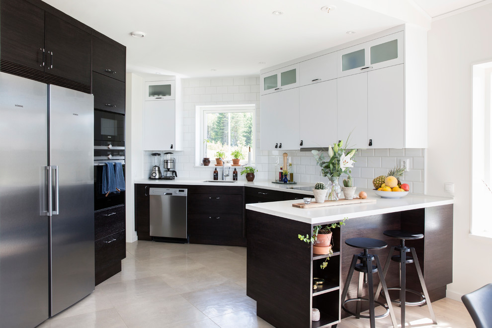 Ejemplo de cocina moderna de tamaño medio con salpicadero de azulejos tipo metro, electrodomésticos de acero inoxidable, península y suelo beige