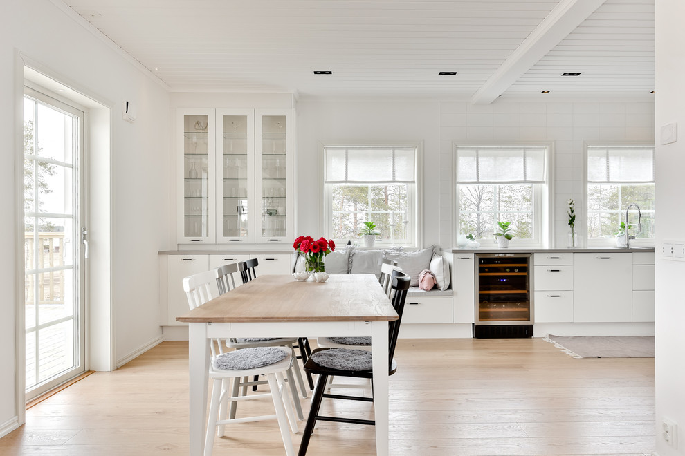 Exemple d'une cuisine américaine chic avec des portes de placard blanches, un plan de travail en granite et un électroménager en acier inoxydable.