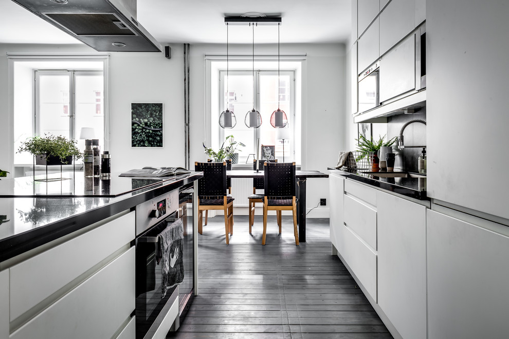 Inspiration for a medium sized scandi galley open plan kitchen in Stockholm with flat-panel cabinets, white cabinets, dark hardwood flooring and a breakfast bar.