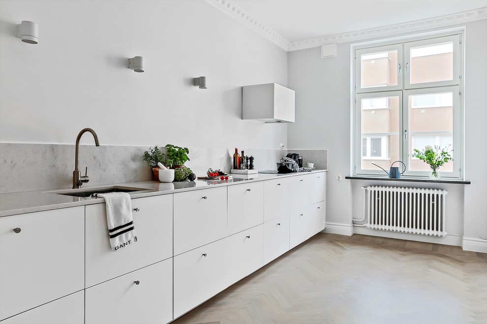 Cette photo montre une cuisine linéaire scandinave avec des portes de placard blanches, aucun îlot, plan de travail en marbre, une crédence blanche et une crédence en marbre.
