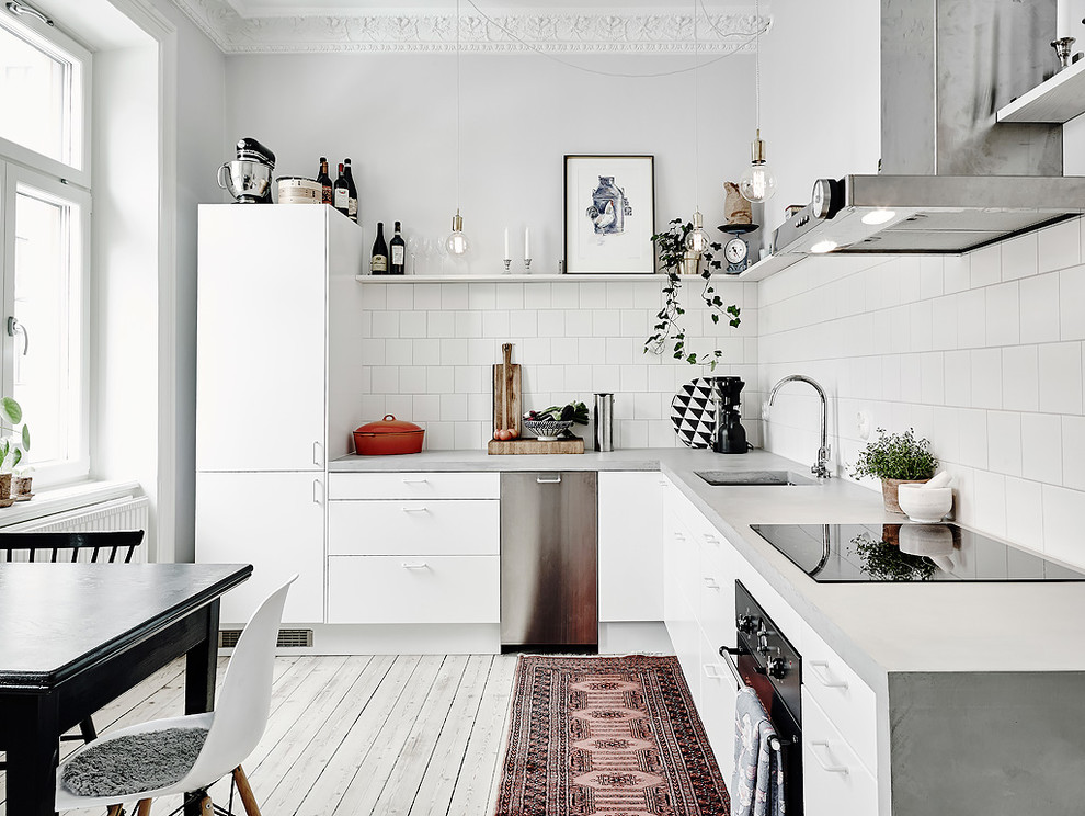 Foto på ett mellanstort vintage l-kök, med en enkel diskho, släta luckor, vita skåp, bänkskiva i betong, rostfria vitvaror och målat trägolv