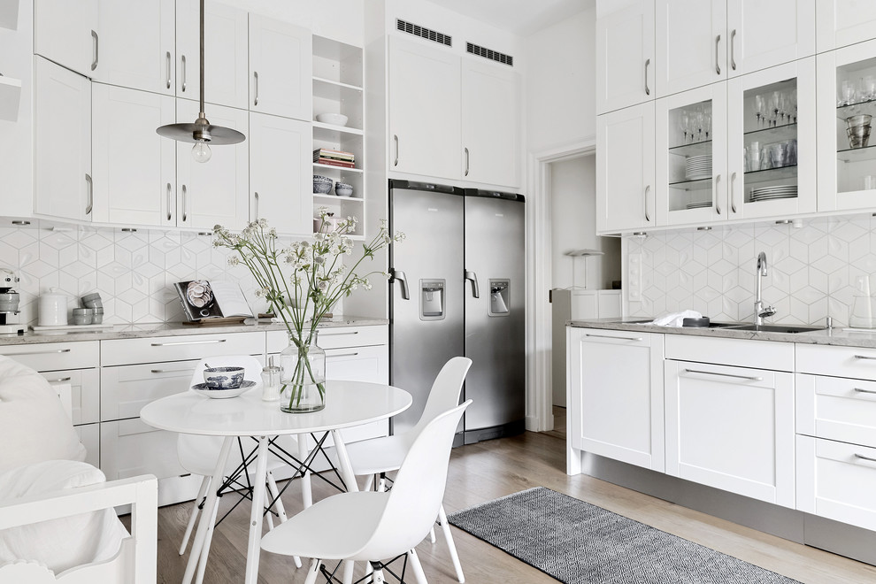 Idéer för att renovera ett mellanstort minimalistiskt kök, med en dubbel diskho, skåp i shakerstil, vita skåp, vitt stänkskydd, rostfria vitvaror, mellanmörkt trägolv och brunt golv