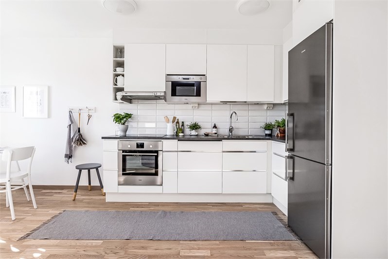 ストックホルムにある北欧スタイルのおしゃれなキッチン (白いキャビネット、ソープストーンカウンター、白いキッチンパネル、ラミネートの床、アイランドなし) の写真