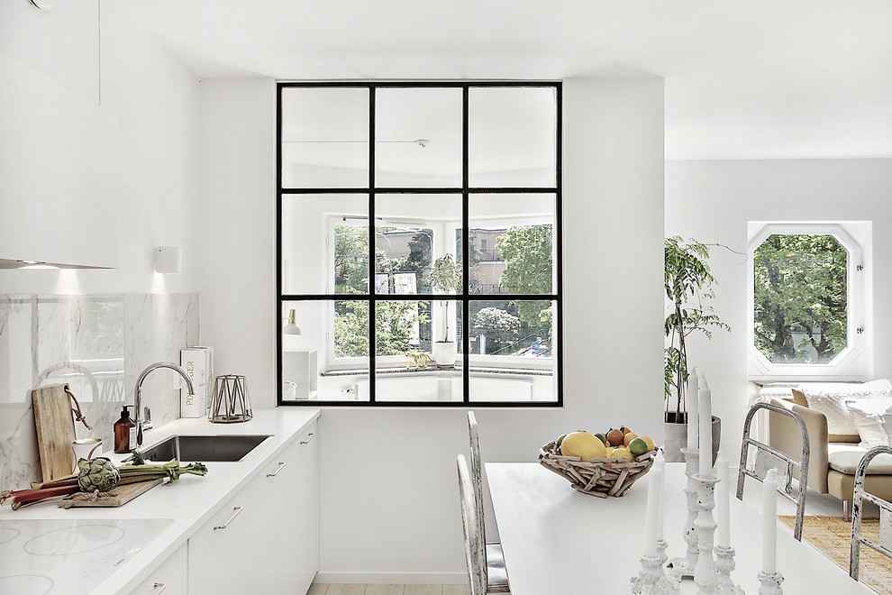 Idéer för ett mellanstort modernt linjärt kök med öppen planlösning, med en enkel diskho, släta luckor, vita skåp, vitt stänkskydd, stänkskydd i marmor, vita vitvaror, ljust trägolv och beiget golv