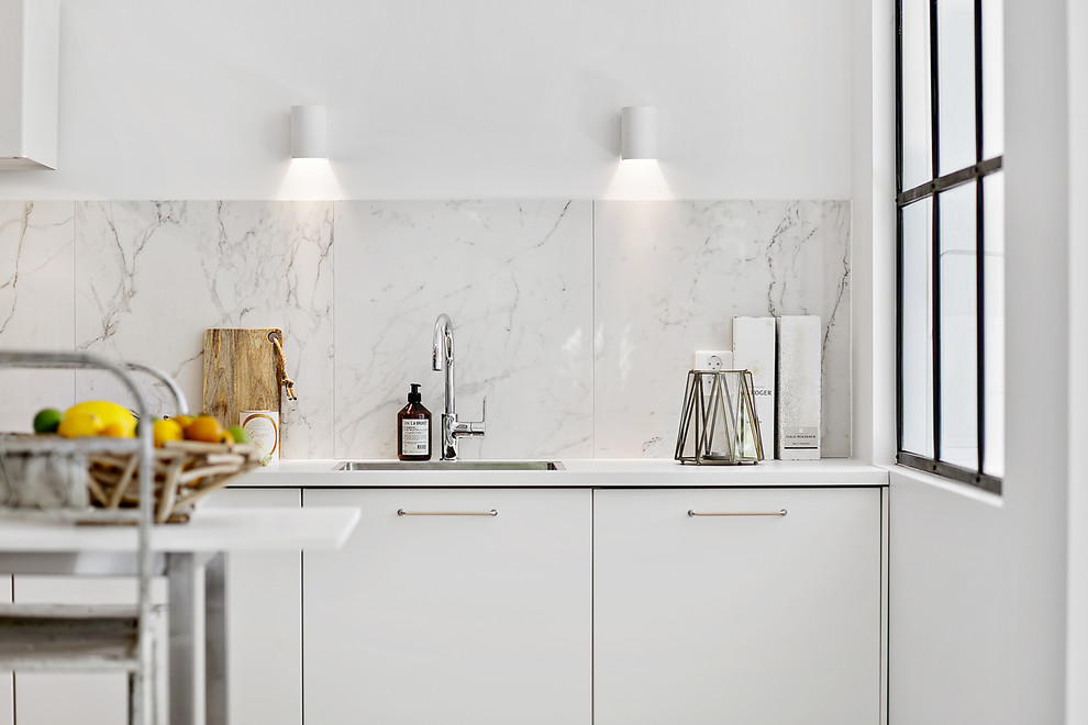 Idéer för att renovera ett mellanstort funkis linjärt kök med öppen planlösning, med en enkel diskho, släta luckor, vita skåp, stänkskydd i marmor och en köksö