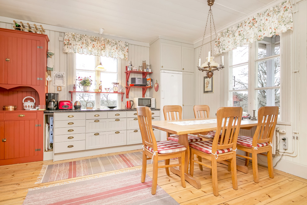 Inspiration for a medium sized rural l-shaped kitchen/diner in Orebro with shaker cabinets, grey cabinets, white appliances, no island and light hardwood flooring.