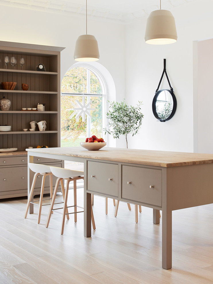 Foto de cocina escandinava de tamaño medio con armarios con rebordes decorativos, suelo de madera clara, una isla y encimera de madera