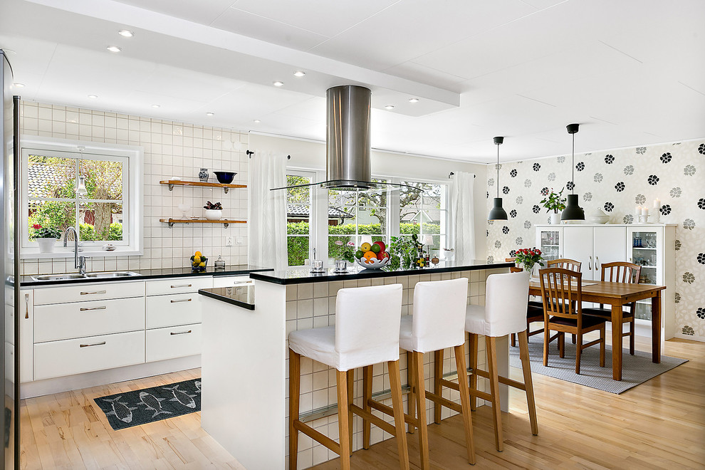 Photo of a large scandi kitchen in Gothenburg with a built-in sink, flat-panel cabinets, white cabinets, white splashback, light hardwood flooring and an island.