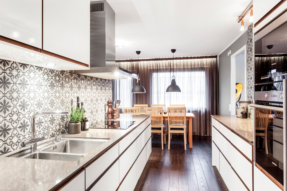 Inredning av ett modernt mellanstort kök, med en dubbel diskho, släta luckor, vita skåp, flerfärgad stänkskydd, stänkskydd i keramik, rostfria vitvaror, mörkt trägolv och brunt golv