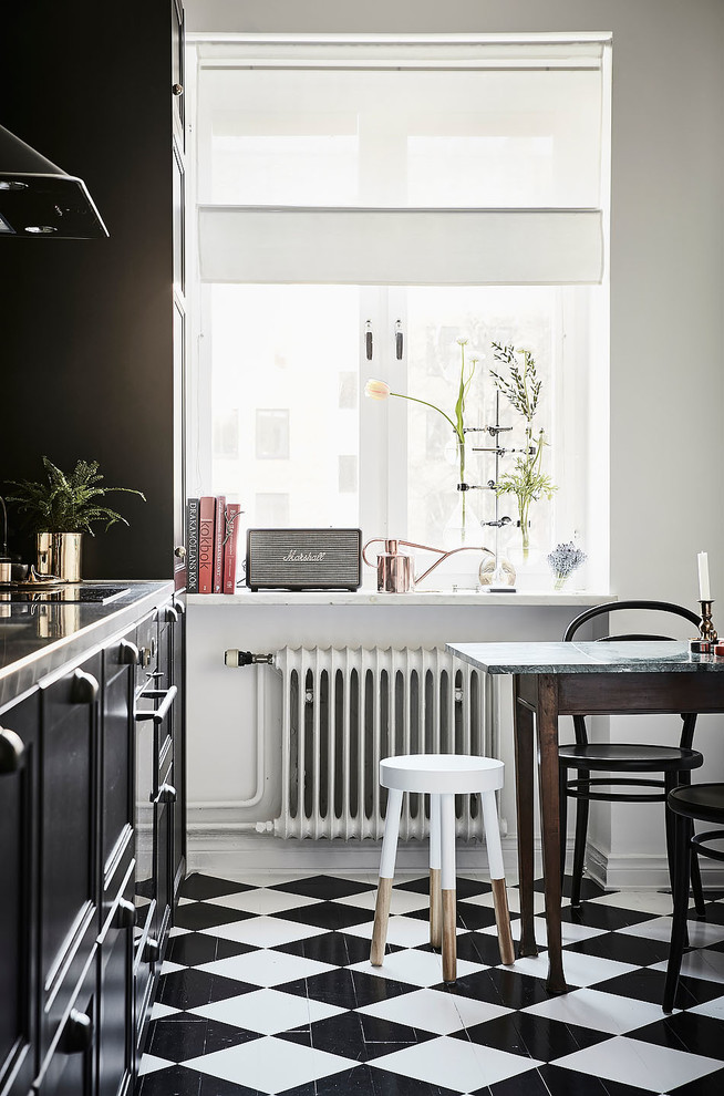 Bild på ett avskilt, litet funkis linjärt kök, med luckor med infälld panel, svarta skåp, marmorbänkskiva, grönt stänkskydd, rostfria vitvaror och flerfärgat golv