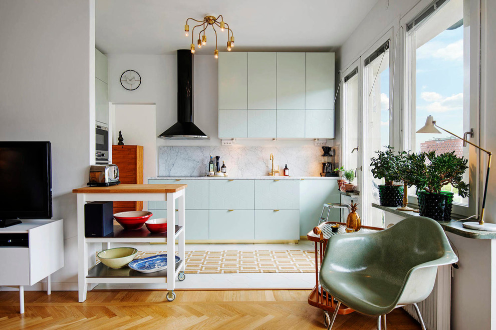 Foto de cocina lineal escandinava de tamaño medio sin isla con armarios abiertos, puertas de armario verdes, encimera de cuarcita, electrodomésticos negros y suelo de madera clara