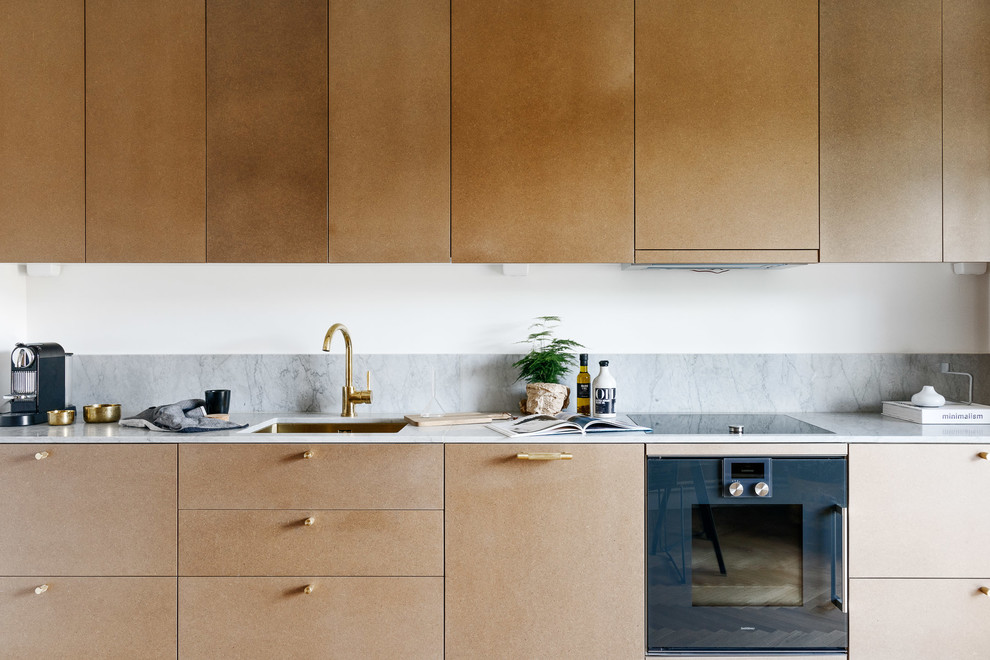 Inredning av ett skandinaviskt stort linjärt kök, med en enkel diskho, släta luckor, beige skåp, marmorbänkskiva och grått stänkskydd