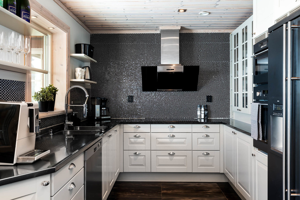 Bild på ett minimalistiskt svart svart u-kök, med en dubbel diskho, luckor med upphöjd panel, vita skåp, svart stänkskydd, stänkskydd i mosaik, rostfria vitvaror och brunt golv
