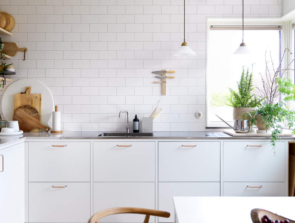 Inspiration for a medium sized scandi l-shaped kitchen/diner in Malmo with a single-bowl sink, flat-panel cabinets, white cabinets, engineered stone countertops and stainless steel appliances.