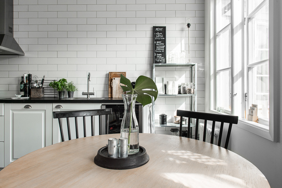 Einzeilige, Kleine Skandinavische Wohnküche ohne Insel mit profilierten Schrankfronten, weißen Schränken, Küchenrückwand in Weiß und Rückwand aus Metrofliesen in Göteborg