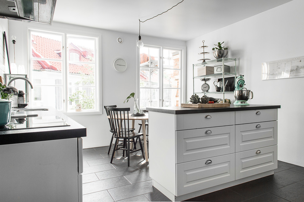 Foto de cocina comedor lineal escandinava con armarios con paneles con relieve, puertas de armario blancas, una isla, encimera de granito y suelo de baldosas de cerámica
