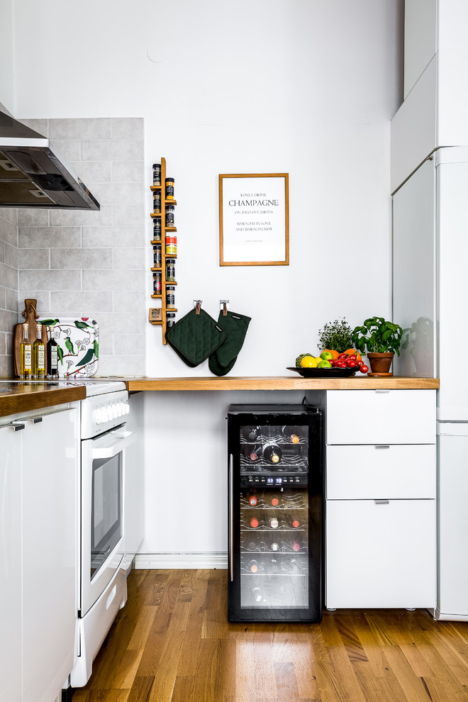 Diseño de cocina escandinava con armarios con paneles lisos, puertas de armario de madera oscura, salpicadero blanco, suelo de madera oscura y suelo marrón