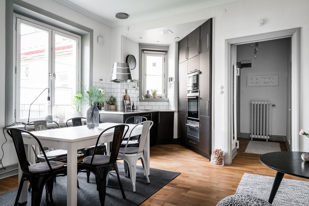 Imagen de cocina escandinava de tamaño medio sin isla con armarios con paneles lisos, salpicadero blanco, suelo de madera en tonos medios y con blanco y negro